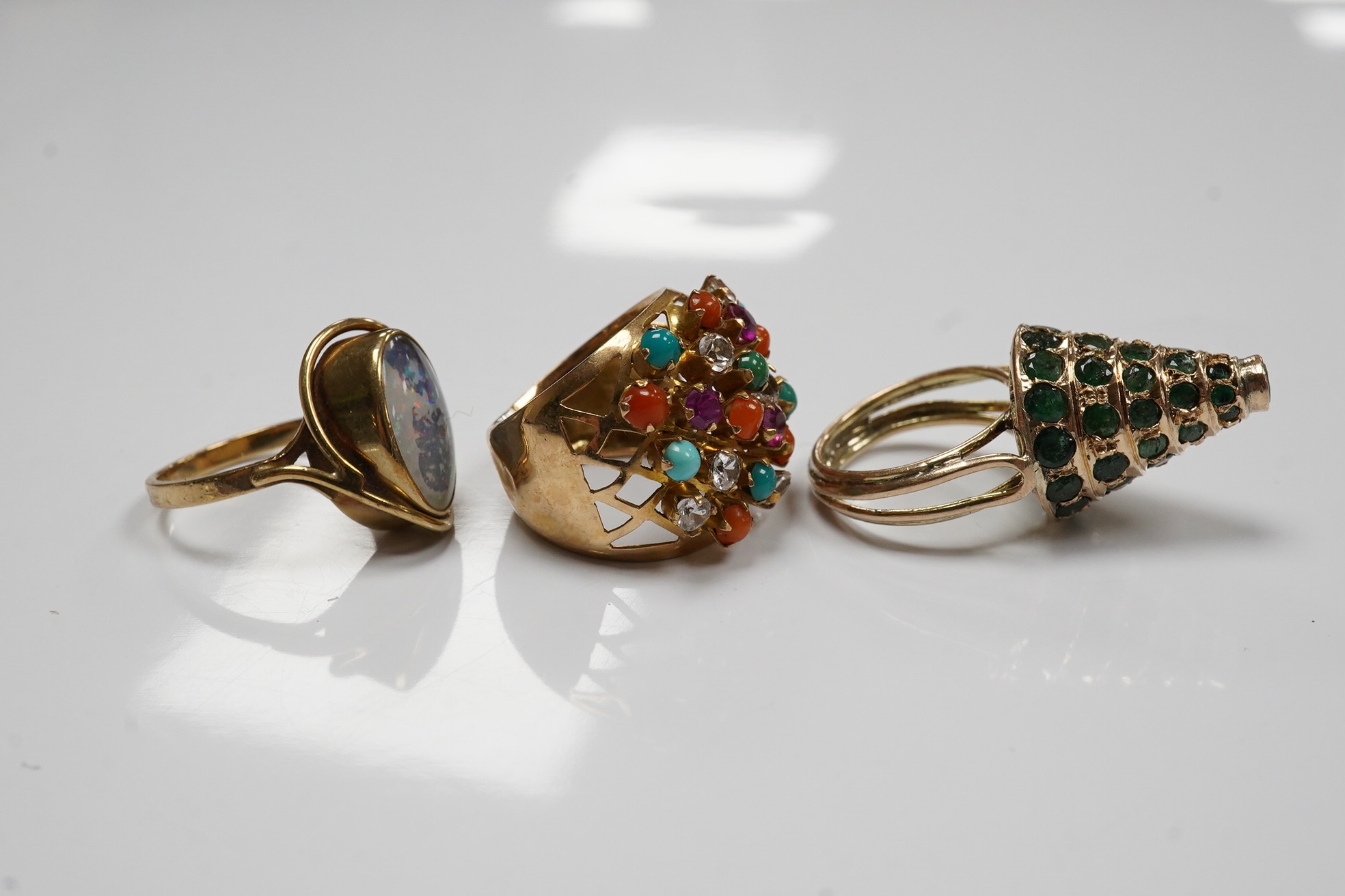 Two Indian? yellow metal and gem set rings including emerald set conical shaped and one other yellow metal and simulated opal set ring. Condition - poor to fair